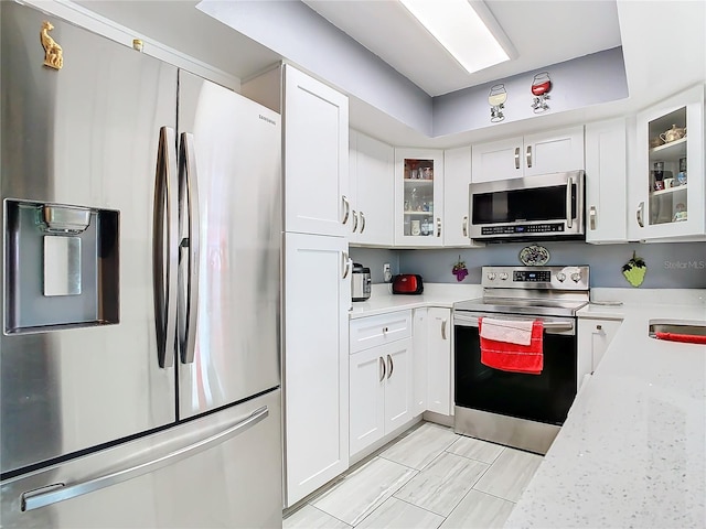 kitchen featuring light stone counters, white cabinets, appliances with stainless steel finishes, and sink