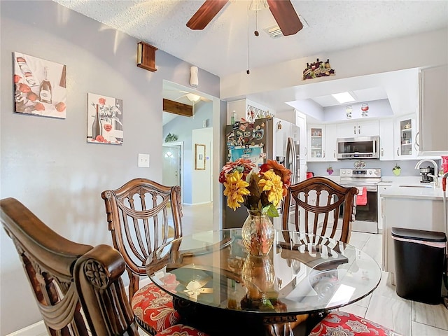 dining room featuring ceiling fan, sink, and a textured ceiling