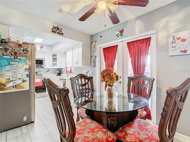 dining space featuring ceiling fan, a skylight, sink, and a textured ceiling