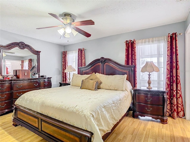 bedroom featuring ceiling fan, light hardwood / wood-style floors, and a textured ceiling