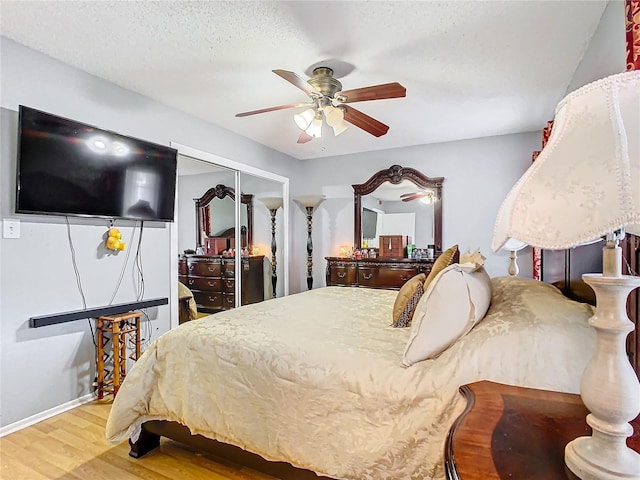 bedroom with a textured ceiling, ceiling fan, a closet, and hardwood / wood-style flooring