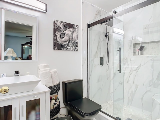 bathroom featuring toilet, vanity, and a shower with door