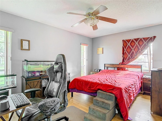 bedroom featuring ceiling fan, multiple windows, and light hardwood / wood-style floors