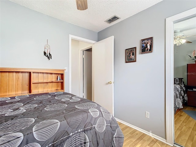 bedroom with ceiling fan, a textured ceiling, and wood-type flooring