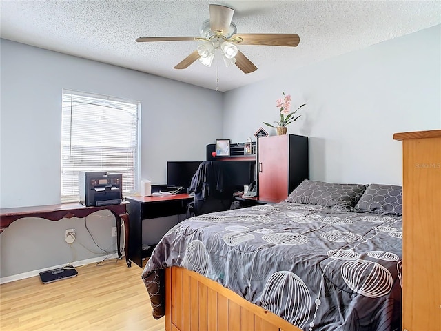 bedroom with ceiling fan, hardwood / wood-style floors, and a textured ceiling