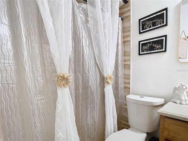 bathroom featuring toilet, vanity, and a shower with shower curtain