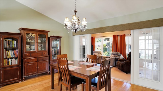 dining space featuring light wood-style floors, a chandelier, and vaulted ceiling