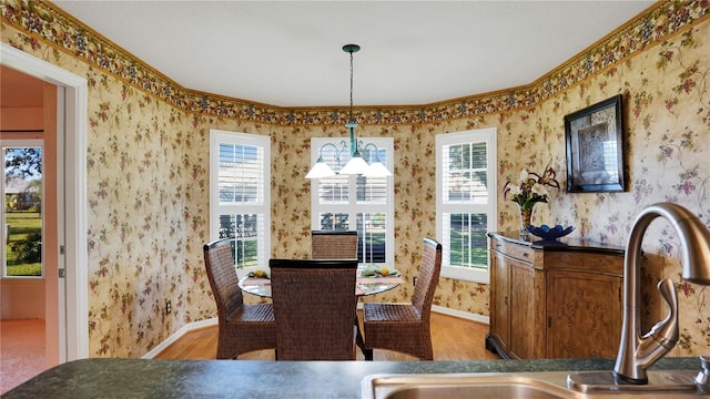 dining room with baseboards, a chandelier, wood finished floors, and wallpapered walls