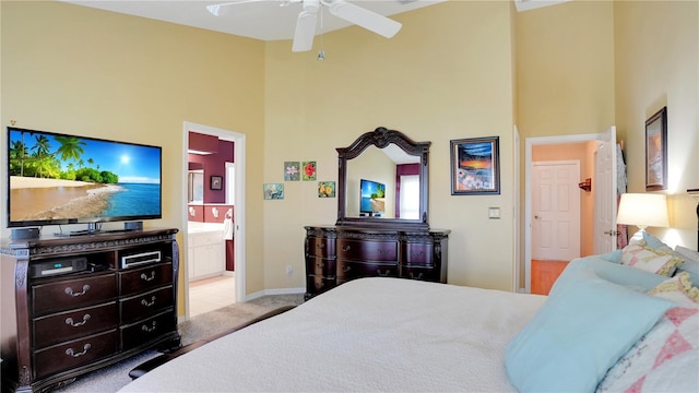 bedroom featuring a towering ceiling, ensuite bath, baseboards, and ceiling fan