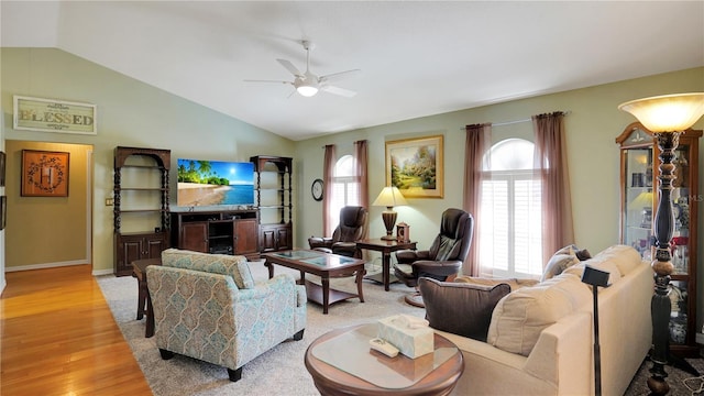 living area featuring ceiling fan, light wood-style flooring, baseboards, and vaulted ceiling