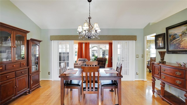 dining area with vaulted ceiling, light wood-type flooring, baseboards, and an inviting chandelier