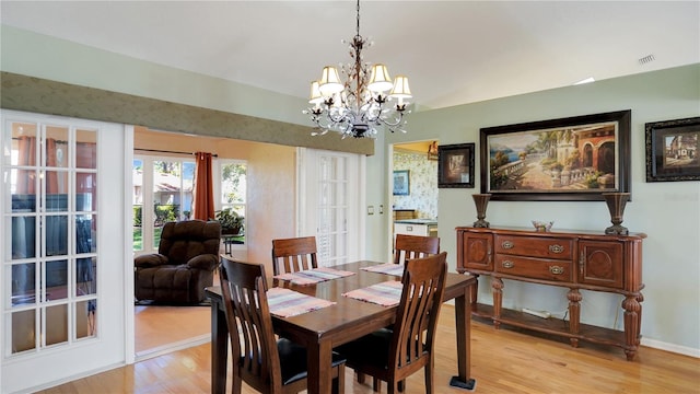 dining space featuring baseboards, light wood finished floors, visible vents, and an inviting chandelier