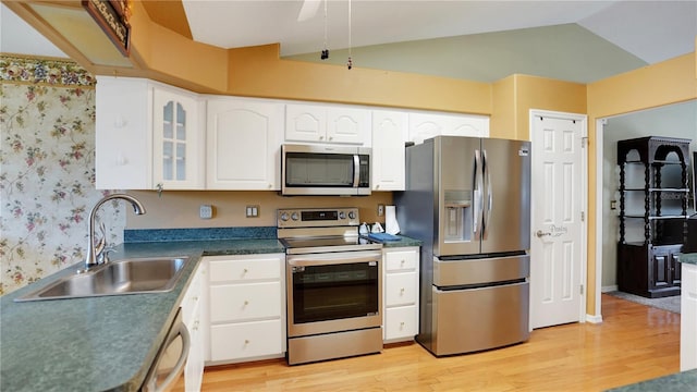 kitchen featuring white cabinets, lofted ceiling, light wood-style flooring, stainless steel appliances, and a sink