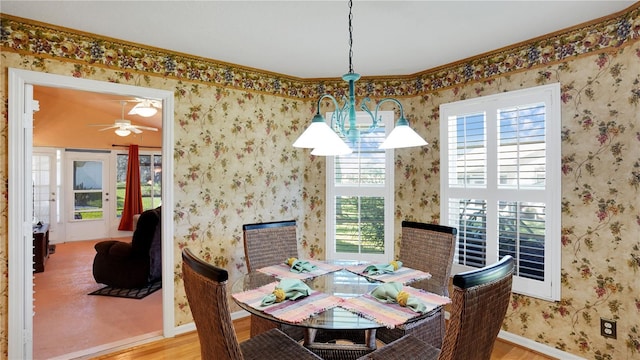 dining room featuring baseboards, ceiling fan, wood finished floors, and wallpapered walls