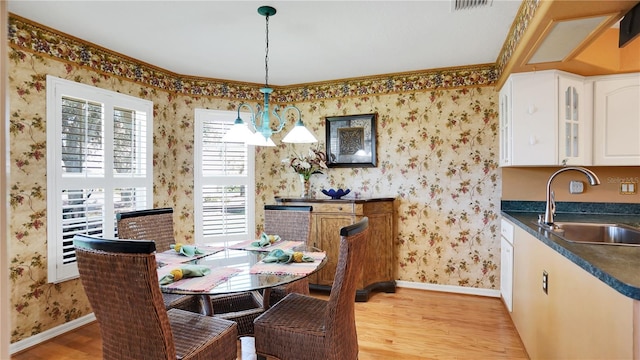 dining space featuring wallpapered walls, baseboards, light wood-style floors, and an inviting chandelier