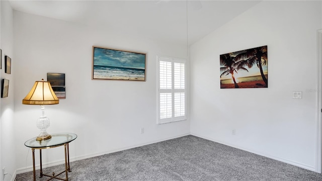 carpeted spare room featuring lofted ceiling and baseboards