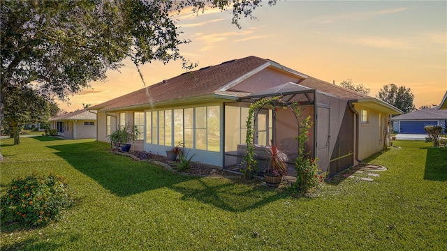 back of house at dusk with a lanai and a lawn