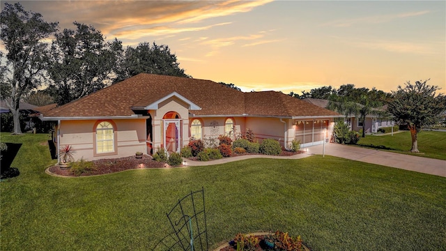 single story home featuring driveway, a front lawn, and stucco siding