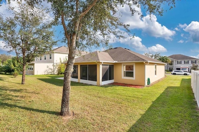 back of property with a yard and a sunroom