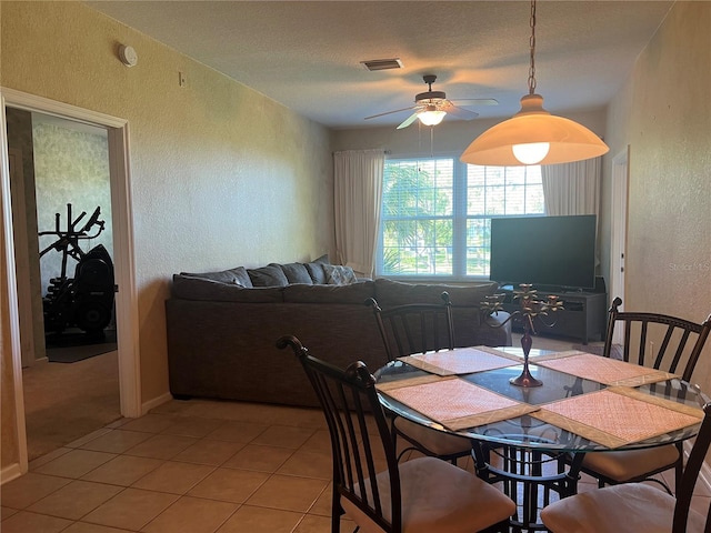 dining area with a textured ceiling, light tile patterned floors, and ceiling fan