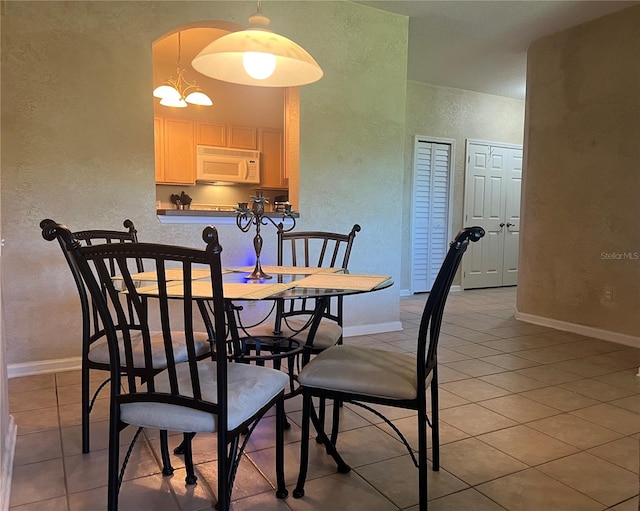 dining area with light tile patterned floors and a chandelier