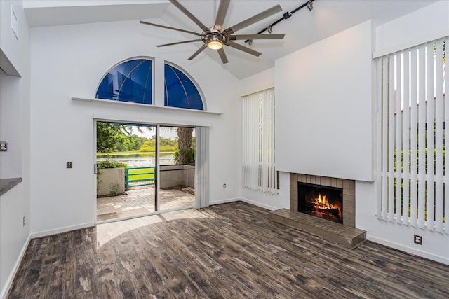 unfurnished living room with high vaulted ceiling, dark wood-type flooring, a fireplace, and ceiling fan