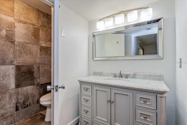 bathroom featuring vanity, toilet, and a textured ceiling