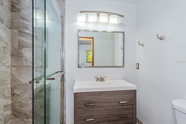 bathroom with toilet, a shower with shower door, and vanity