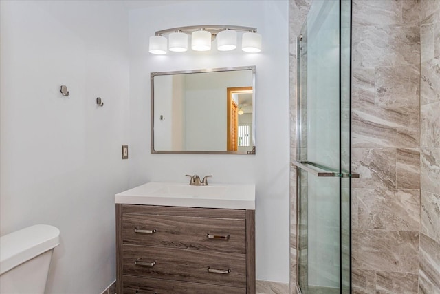 bathroom featuring a shower with door, vanity, and toilet