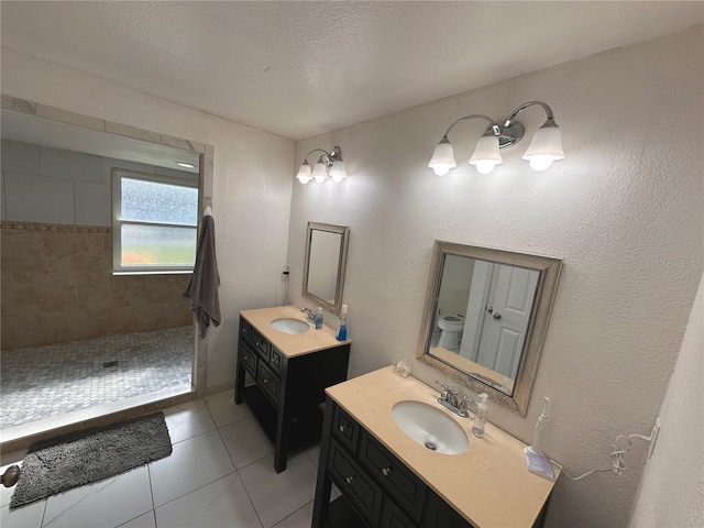 bathroom featuring a tile shower, a textured ceiling, toilet, vanity, and tile patterned flooring