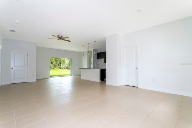 unfurnished living room featuring sink, light tile patterned flooring, and ceiling fan