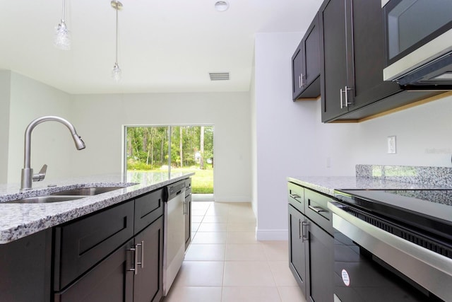 kitchen featuring light tile patterned floors, stainless steel dishwasher, stove, pendant lighting, and light stone counters