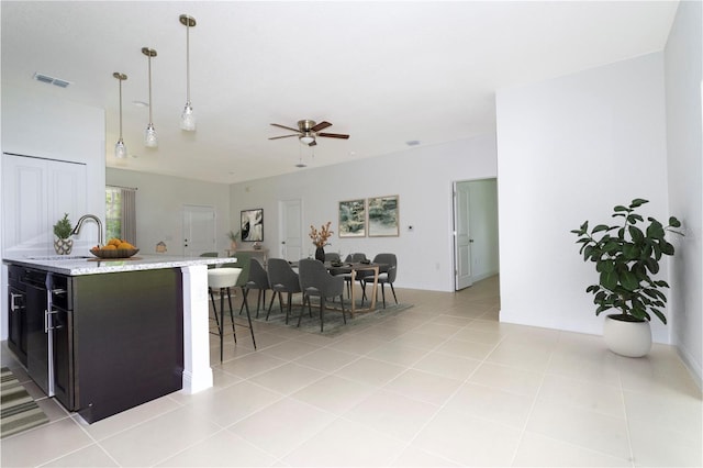 kitchen featuring light stone countertops, light tile patterned flooring, hanging light fixtures, and sink