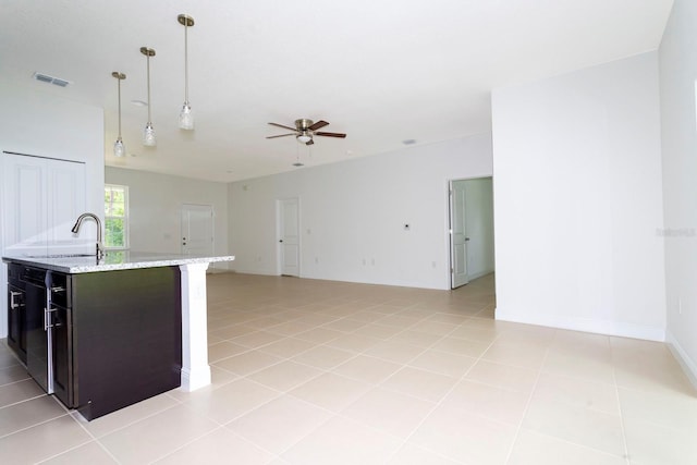 kitchen with sink, light stone countertops, hanging light fixtures, and light tile patterned floors