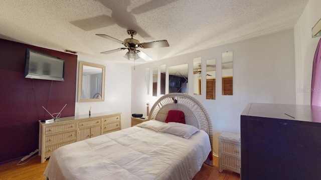 bedroom with ceiling fan, a textured ceiling, and hardwood / wood-style floors