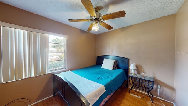 bedroom featuring ceiling fan, a textured ceiling, and dark hardwood / wood-style flooring