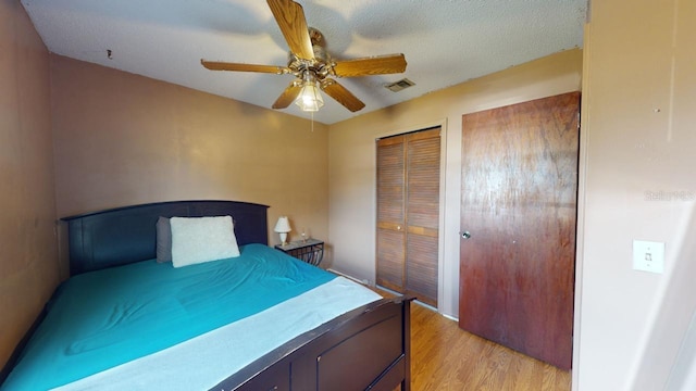 bedroom featuring a closet, a textured ceiling, light wood-type flooring, and ceiling fan