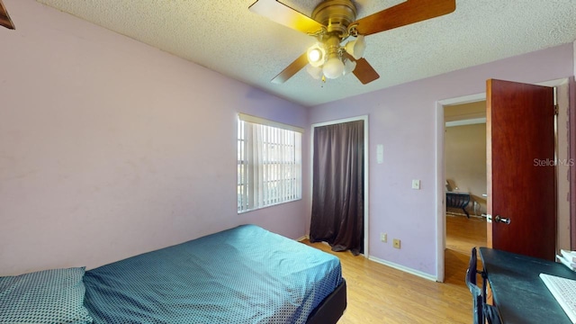 bedroom featuring ceiling fan, a textured ceiling, and light wood-type flooring