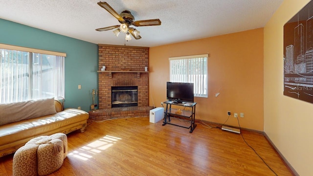 living room featuring light hardwood / wood-style flooring, a textured ceiling, a healthy amount of sunlight, and a fireplace