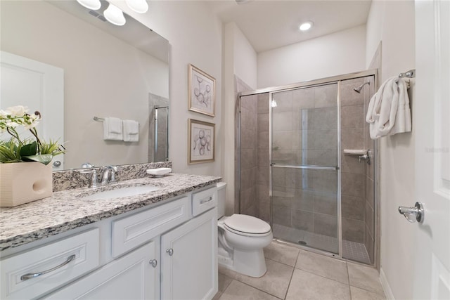 bathroom featuring toilet, a shower with shower door, vanity, and tile patterned flooring