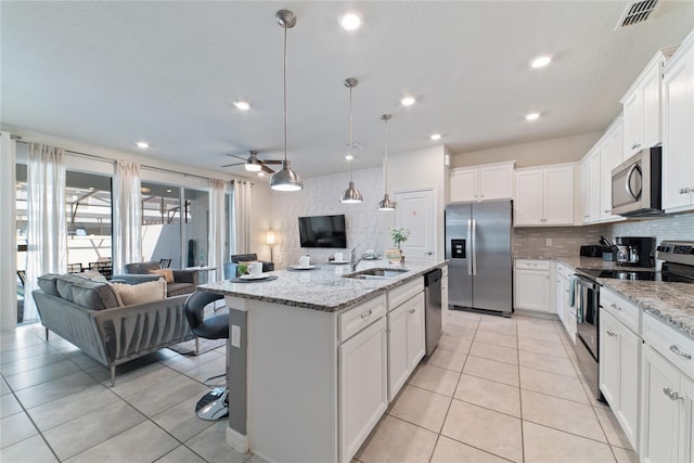 kitchen featuring sink, stainless steel appliances, pendant lighting, white cabinets, and a center island with sink