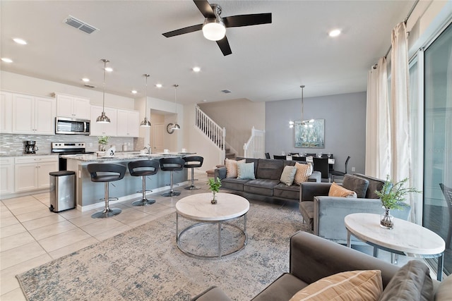 living room featuring ceiling fan with notable chandelier and light tile patterned floors