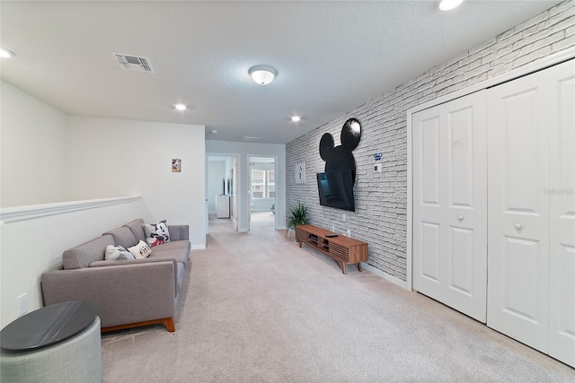 living room with a textured ceiling, light colored carpet, and brick wall