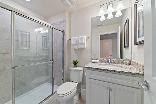 bathroom featuring toilet, a shower with shower door, and vanity