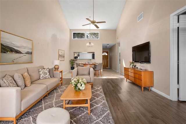 living room featuring dark hardwood / wood-style floors, high vaulted ceiling, and ceiling fan with notable chandelier