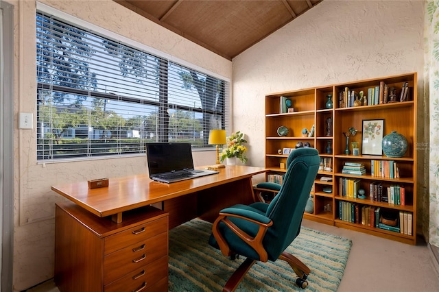 office featuring lofted ceiling, concrete flooring, and plenty of natural light