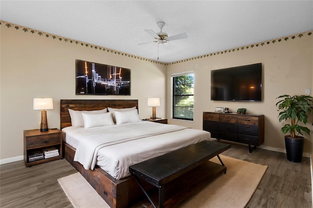 bedroom featuring ceiling fan, hardwood / wood-style flooring, and a textured ceiling