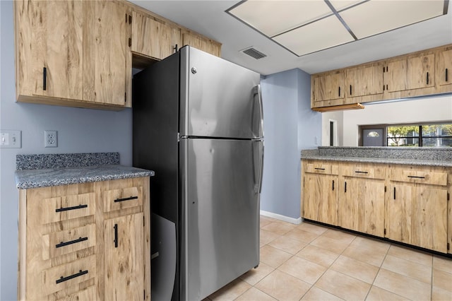 kitchen featuring light brown cabinets, stainless steel fridge, and light tile patterned flooring