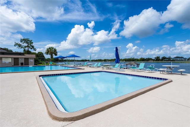 view of swimming pool with a patio area and a water view