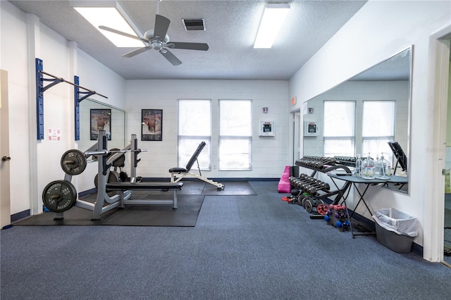 exercise area with ceiling fan, a textured ceiling, plenty of natural light, and dark carpet